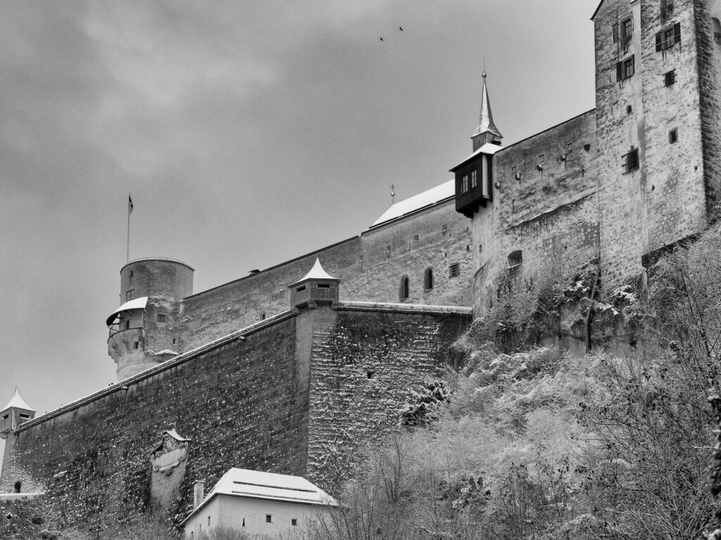 Blick auf die leicht schneebedeckte Festung Hohensalzburg von unten in schwarz-weiß.