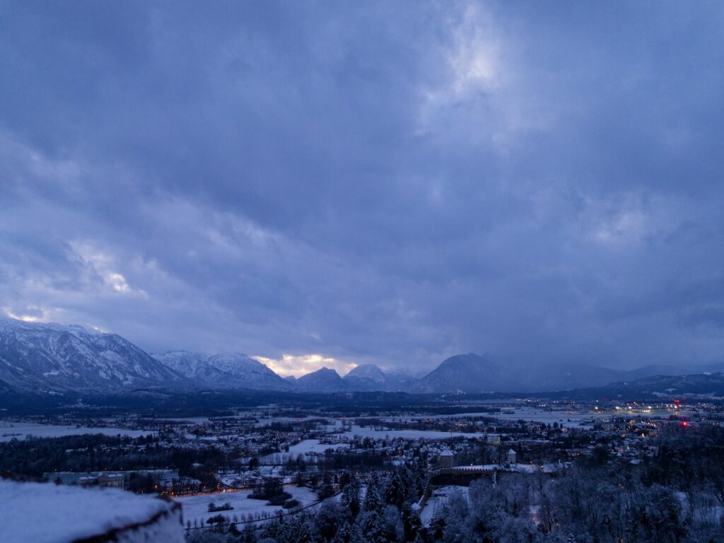 Blick von der Festung Salzburg Richtung Flughafen in der Abenddämmerungunter dunklen Wolken.