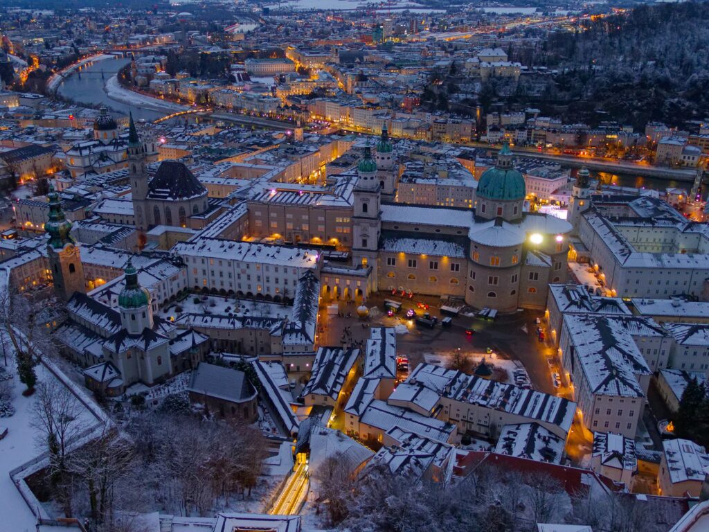 Salzburg: Blick auf den Kapitelplatz und Dom in der Abenddämmerung mit schneebedeckten Dächern.