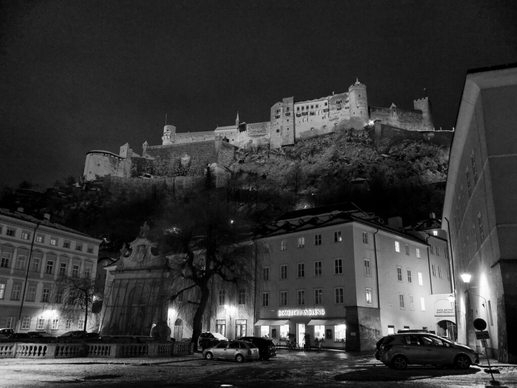 Blick vom Kapitelplatz auf die Festung Salzburg bei Nacht in schwarz-weiß.